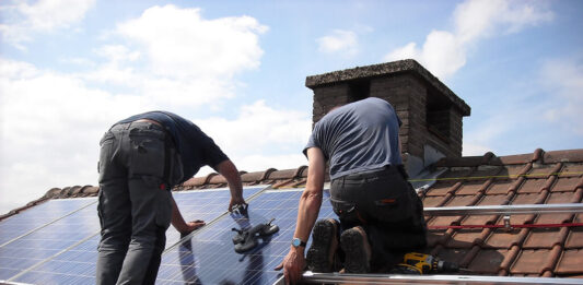 Ludzie na dachu montujący panele